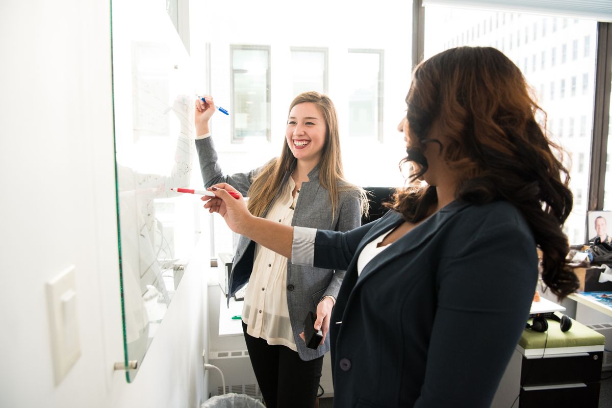 Two colleagues working through ideas together at a whiteboard.